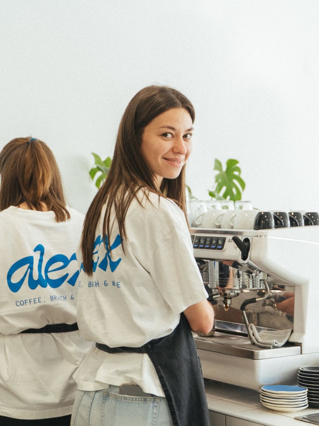 Baristas do Alex junto à máquina de café, com t-shirts com o logótipo azul
